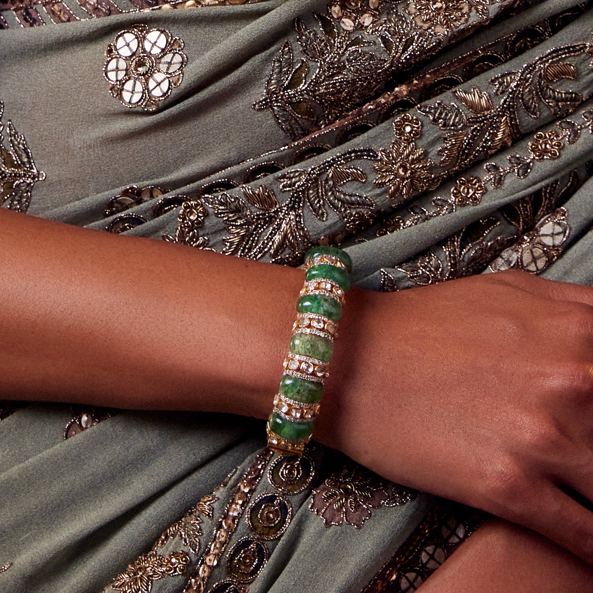 Gold bangle with rounded emerald beads and Polki stones, perfect for a regal touch.