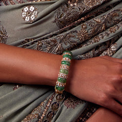 Gold bangle with rounded emerald beads and Polki stones, perfect for a regal touch.